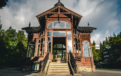 Drewniany pawilon w Karlovej Studance, ozdobiony lampkami, zaprasza do środka. Wspaniała architektura i otoczenie lasu tworzą magiczną atmosferę.