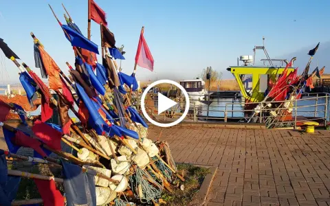 Stos kolorowych flag rybackich i bojki na nabrzeżu przy łodziach.