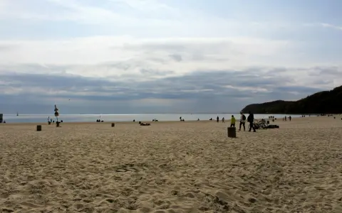 Plaża z ludźmi spacerującymi i odpoczywającymi. Idealny pomysł na weekend nad morzem.