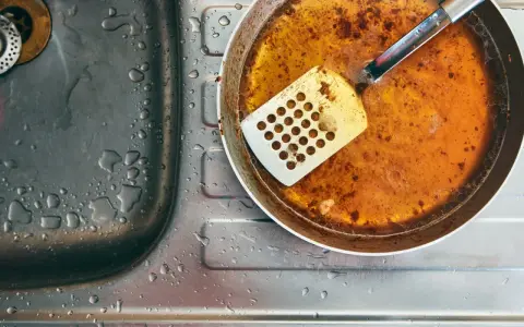 Zlepek zużytego oleju gastronomicznego na patelni obok zlewu.