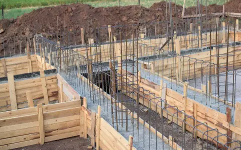 Drewniany szalunek fundamentowy z zbrojeniem stalowym, gotowy do wylania betonu.