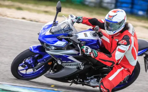 Motocyklista w czerwonym kombinezonie i kasku ściga się na torze na motocyklu Yamaha R3.