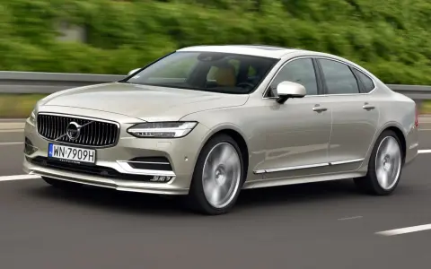 Eleganckie Volvo S90 w kolorze szampańskim pędzi po drodze. Choć piękny, warto pamiętać o potencjalnych wadach tego modelu.