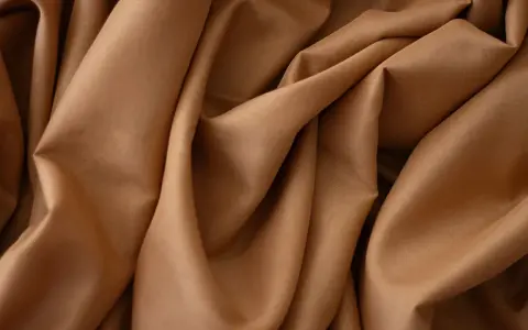 Tessuto in crepe color caramello, ideale per abiti eleganti, sia estivi che invernali, grazie alla sua caduta fluida.