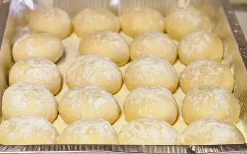 Piccolo pane fatto in casa, soffice e leggermente infarinato, pronto per essere infornato.
