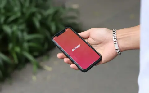 Dłoń trzyma smartfon z otwartą aplikacją Tinder. Zastanawiasz się, jak znaleźć osobę z Tindera na Facebooku?