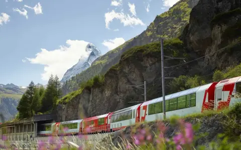 The Glacier Express train winds through the Swiss Alps, with the Matterhorn in the distance. Is the Glacier Express worth it? This view suggests yes!