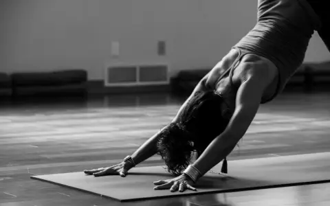 En person utför en nedåtgående hund-position under kundalini yoga.