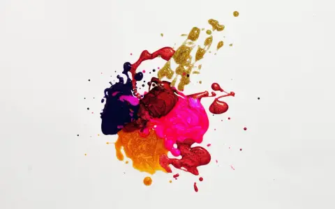 Salpicaduras de pintura vibrante en tonos morado, rosa, rojo y dorado, creando un patrón abstracto y dinámico sobre fondo blanco.