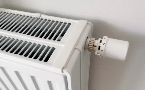 Biały grzejnik z termostatem. Dowiedz się, jak odpowietrzyć grzejnik, gdy przestaje efektywnie grzać.