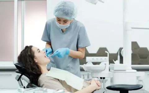 Dentystka bada zęby pacjentki, szukając oznak problemów, które mogą wymagać leczenia kieszonek dziąsłowych.