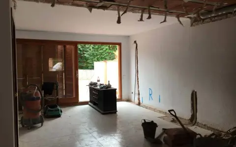 Interior de una casa de pueblo en plena reforma. Se ven materiales de construcción, herramientas y un aspirador.