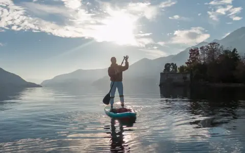 Person auf einem Stand Up Paddle Board, genießt die Aussicht und verbrennt dabei effektiv Stand Up Paddle Kalorien.