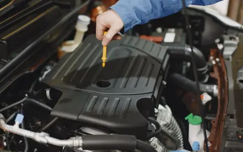 Mechanik sprawdza poziom oleju w silniku Peugeot 508. Wymiana oleju w skrzyni manualnej to ważny element dbania o auto.