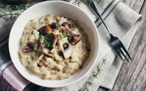 Risotto crémeux aux champignons, garni de thym frais. Une alternative savoureuse au vin blanc pour un risotto parfait.