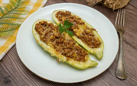 Dos mitades de calabacines rellenos de carne picada y queso gratinado, decorados con perejil. Un plato casero y delicioso.
