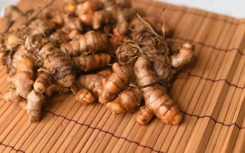 Kłącza kurkumy, znanej jako turmeric co to, leżą na bambusowej macie.