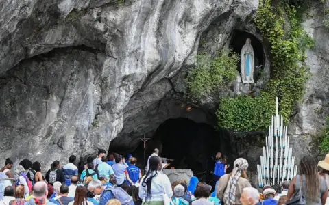 Pielgrzymi gromadzą się przed Grotą Massabielle w Lourdes, by złożyć modlitwę do Matki Bożej z Lourdes o uzdrowienie.