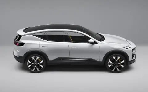 Srebrny SUV Polestar 3 z czarnym dachem i żółtymi zaciskami hamulcowymi, widziany z boku.