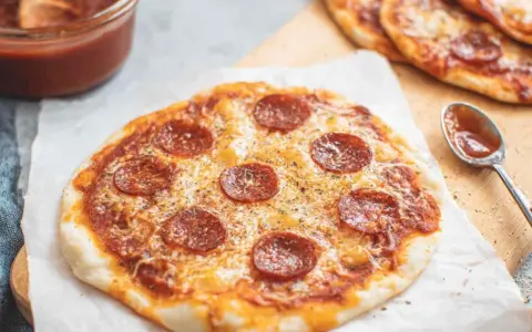 Pyszna pizza z tortilli z pepperoni i serem, obok sos pomidorowy i łyżeczka.