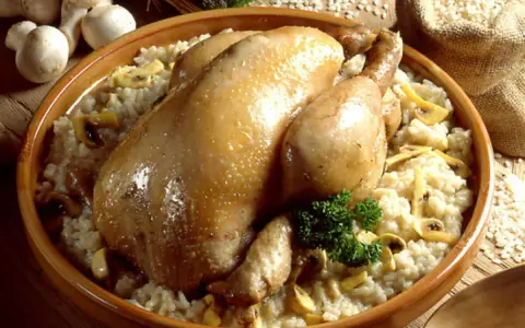 Un plat réconfortant de poule au riz crémeux, garni de champignons et d'une touche de persil frais.