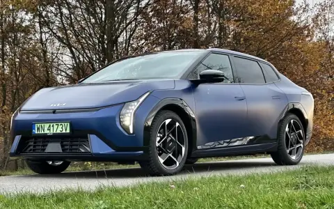 Niebieski Polestar 2 na tle jesiennych drzew. Elegancki samochód elektryczny z charakterystycznymi światłami i felgami.