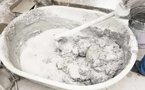 Mieszanie wapna gaszonego w dużej misie, tworząc gładką masę do prac budowlanych.