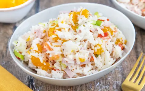 Omas Reissalat mit Orangenstücken, Schinkenwürfeln und Frühlingszwiebeln in einer Schüssel.