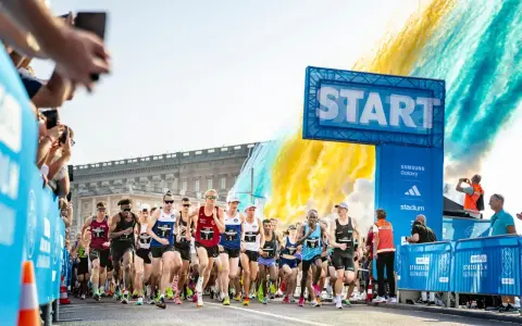Löpare startar adidas halvmarathon i Stockholm. Publiken hejar och färgexplosioner lyser upp himlen.