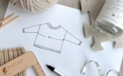 Esquema de jersey con medidas, ovillo de lana, agujas, cinta métrica y regla. Ideal para un top crochet tutorial.