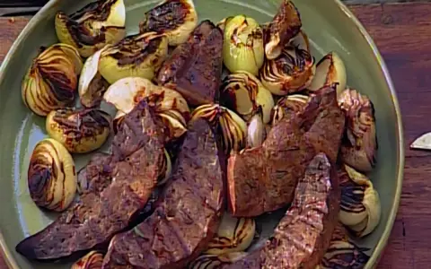 Sabroso hígado encebollado a la parrilla, con trozos de cebolla caramelizada y tiernas lonchas de hígado.
