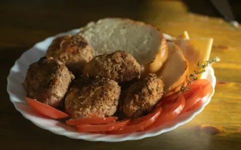 Talerz z kotletami mielonymi, kromkami chleba, pomidorami i serem. Idealny posiłek, jeśli zastanawiasz się, jaki kotlet mielony kcal.