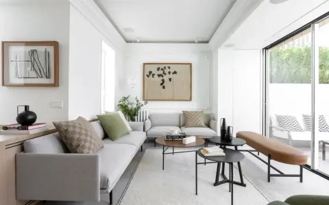 Salón moderno con sofás grises, mesas bajas y acceso directo a una terraza, creando un espacio fluido para unir terraza y salón.