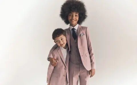 Two boys in matching dusty rose suits, showing what ring bearers wear: tailored jackets, vests, shirts, and ties.