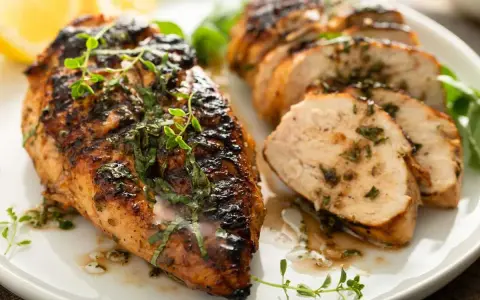 Delicioso pollo a la parrilla jugoso y tierno, con hierbas frescas y limón, servido en un plato blanco.
