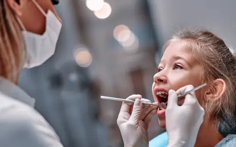 Mała dziewczynka u dentysty. Czas na kontrolę, kiedy wypadają trójki mleczne.