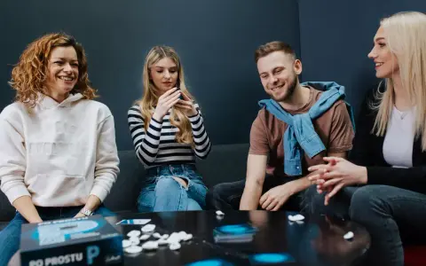 Radosne spotkanie z przyjaciółmi przy planszówce. Uśmiechy, rozmowy i wspólna zabawa.