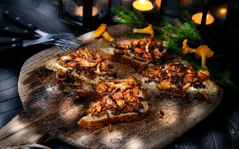 Smörstekta kantareller på bröd, ett enkelt och gott kantareller recept. Serveras på en träbricka med ljus och granris.