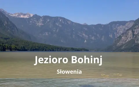 Spokojne jezioro Bohinj w Słowenii otoczone zielonymi wzgórzami i skalistymi górami.