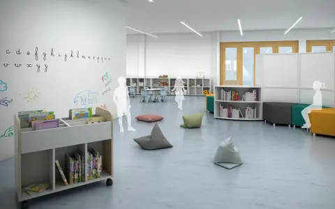 Plano de aula infantil con estanterías, libros, pufs y dibujos en la pared.