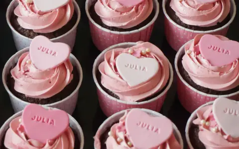 Rosa cupcakes med hjärtformade dekorationer med texten "JULIA". Perfekt för en speciell Julia!