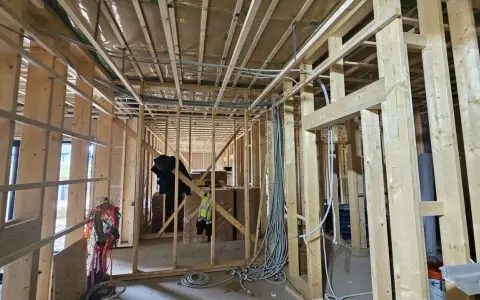 Widok wnętrza domu drewnianego w budowie. Widoczna instalacja elektryczna, drewniane ściany i stropy. Przepisy dotyczące instalacji elektrycznej w domach drewnianych są kluczowe dla bezpieczeństwa.