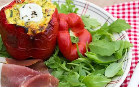 Poivrons farcis à l'italienne, garnis d'une préparation savoureuse et surmontés d'une touche de crème fraîche. Servi avec roquette et fines tranches de jambon.