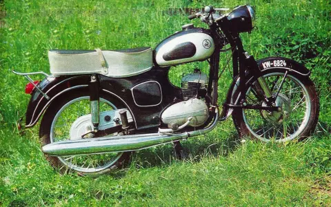 Klasyczny motocykl SHL M11 na tle zielonej trawy. Poznaj jego shl m11 dane techniczne i poczuj ducha minionej epoki.