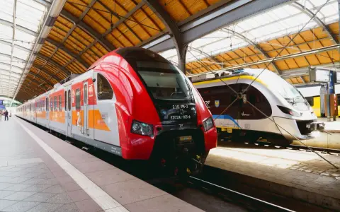 Dwa nowoczesne pociągi, czerwony i srebrny, czekają na pasażerów na dworcu. To idealny pociąg do poznania nowych miejsc.
