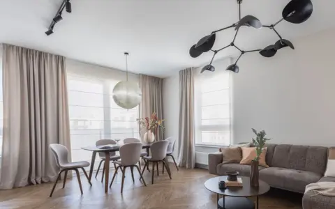 Nowoczesne oświetlenie salonu z jadalnią: designerski żyrandol i reflektory nad stołem. Aranżacje wnętrz z klasą.