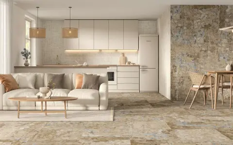 Elegante salón-cocina con sofá beige, mesa de centro de madera y suelos de cemento con un diseño rústico y texturizado.
