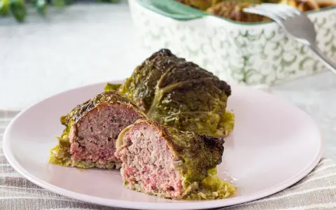 Involtini di verza con carne succulenta, uno tagliato a metà per mostrare il ripieno saporito.
