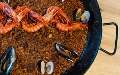 Paella de marisco con gambas rojas, mejillones y almejas sobre arroz dorado.