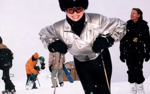 Ivana Trump joven, sonriendo y esquiando con un gorro de piel y gafas de esquí. A su alrededor, otras personas disfrutan de la nieve.